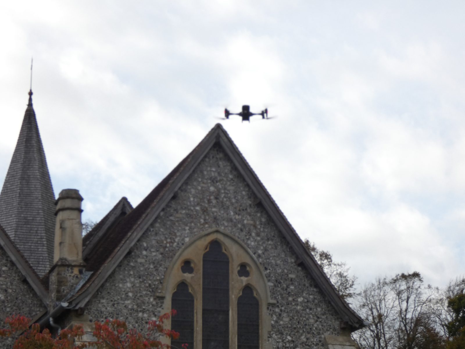 Survey drone flying above a flint church roof and spire